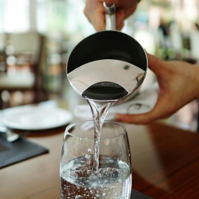 Close-up of water being poured into a glass in a restaurant setting.